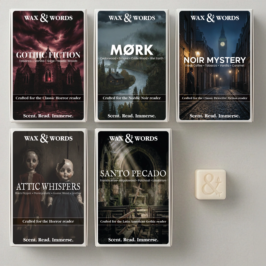 Six boxed card decks from Wax & Words arranged on a light gray surface, plus one small cream-colored card or tile at lower right. The boxes feature dark illustrated covers for Gothic Fiction, Mørk, Noir Mystery, Attic Whispers, Santo Pecado, and a dark gothic title.