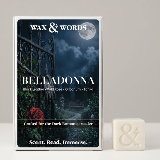 A boxed fragrance product labeled 'Wax & Words' and 'Belladonna' stands upright on a light neutral surface, with a small off-white bar of soap or wax cube placed beside it. The box artwork shows a dark gothic night scene with a full moon, wrought iron gate, cloudy sky, and a red rose.