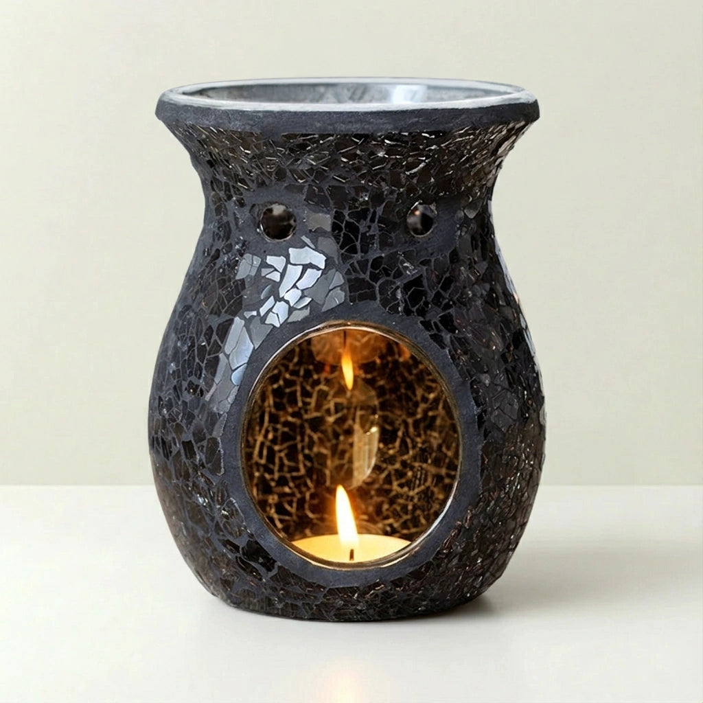 Black mosaic candle warmer with a lit candle inside on a white background