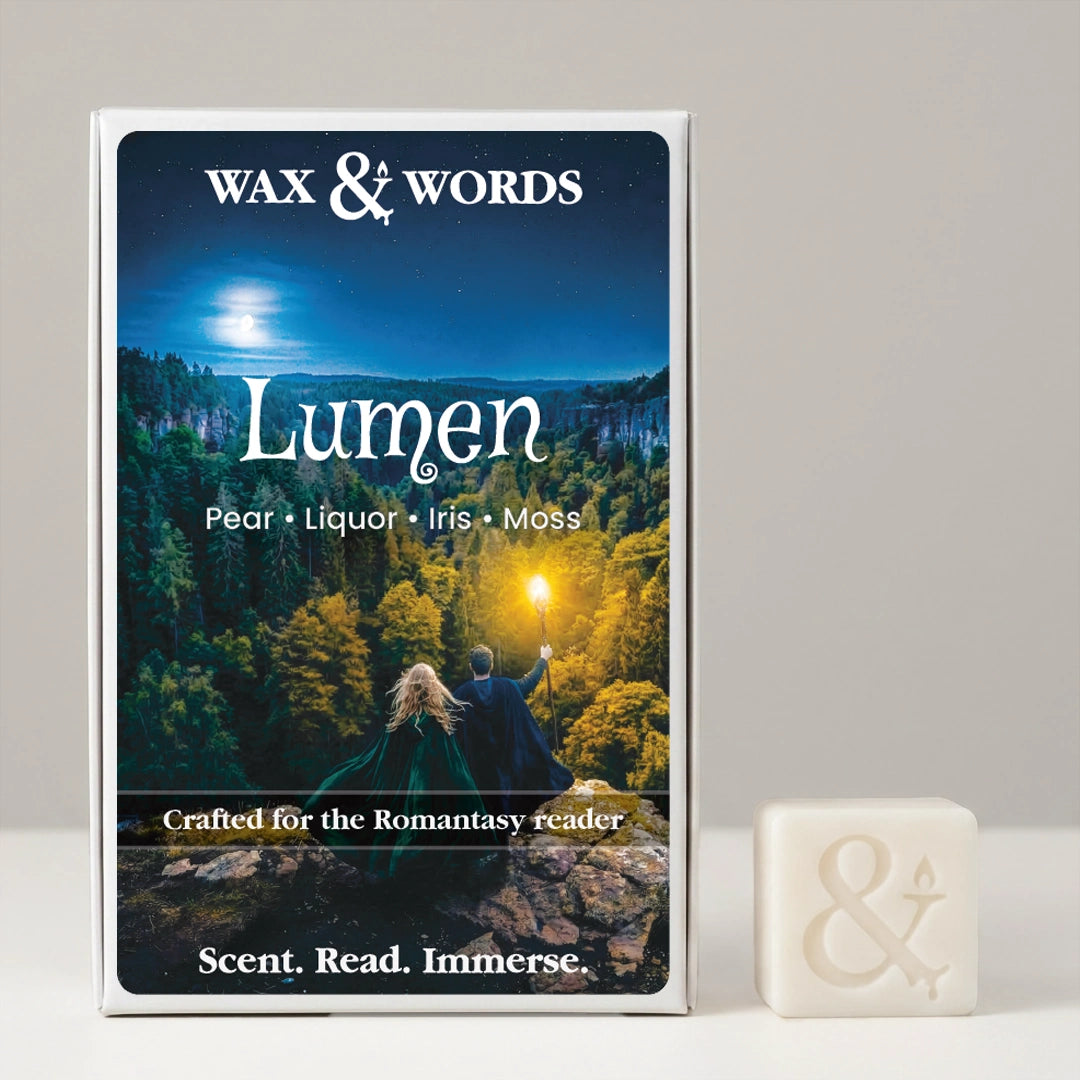 Wax & Words 'Lumen' book or scent box with a fantasy forest cover, shown standing upright next to a small white cube with an ampersand symbol on a light gray background.