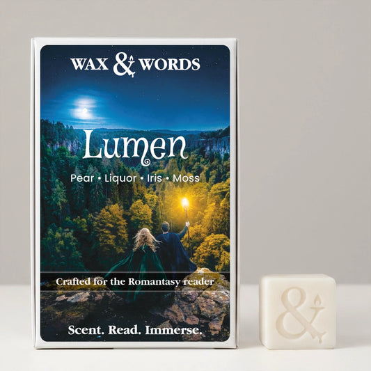 Wax & Words 'Lumen' book or scent box with a fantasy forest cover, shown standing upright next to a small white cube with an ampersand symbol on a light gray background.