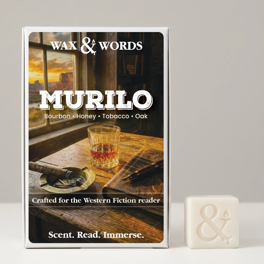 A boxed fragrance product labeled 'Wax & Words Murilo' stands upright on a light gray surface against a light gray background, with a small off-white wax cube beside it. The box front shows a warm-toned scene with a whiskey glass, cigar, and sunset window, and the scent notes 'Bourbon • Honey • Tobacco • Oak.